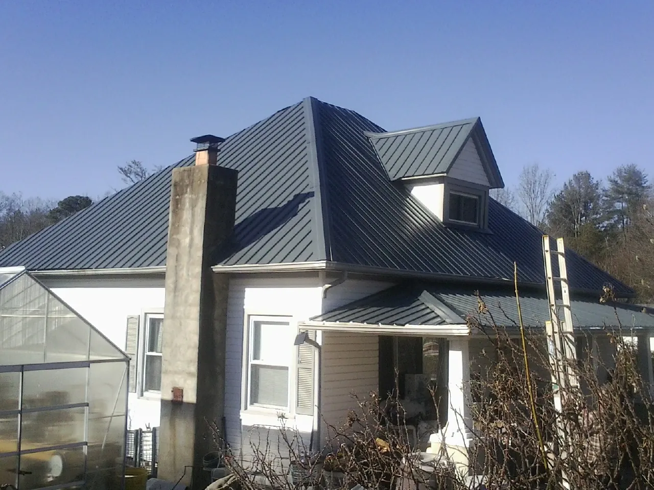 Dark blue standing seam metal roof on a white farmhouse with dormer — Slate & Tile Roof Repair by Roofing Brothers in Muncie
