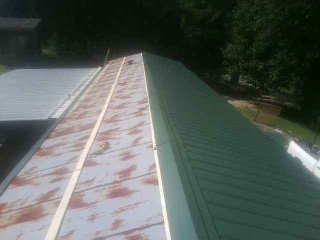 Old rusted panels beside newly installed green metal roofing — Wind Damage Roof Repair by Roofing Brothers in Muncie