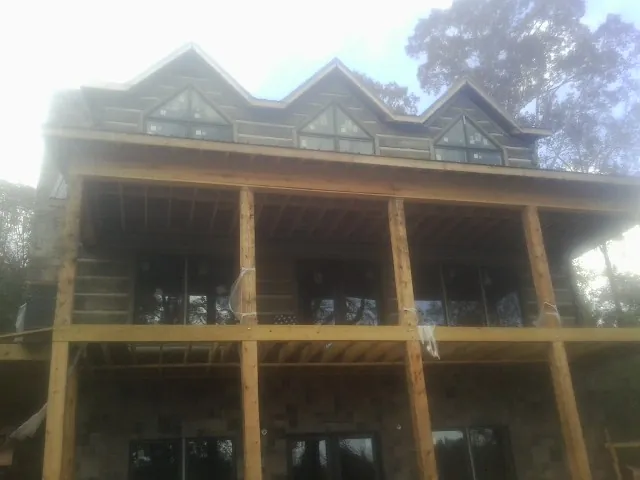 Dormers and porch framing on a large log home under construction — Roof Coating work by our crew in Muncie