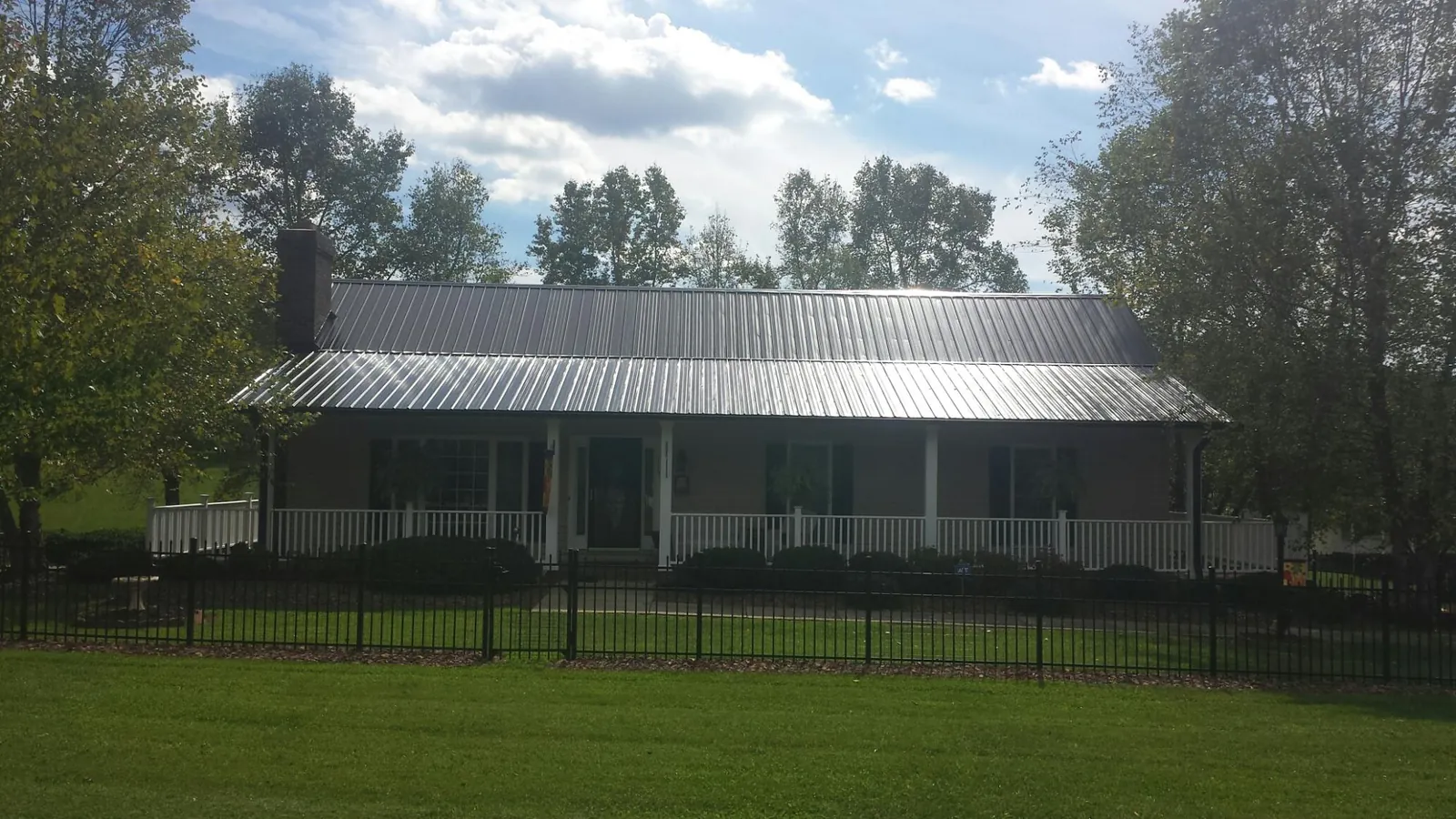 Gray metal roof on a brick ranch with a full width front porch — Gutter Guard Installation work by our crew in Muncie