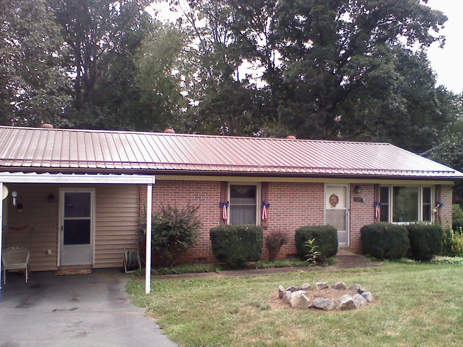 Bronze metal roof and carport on a brick ranch home — Roof Repair work by our crew in Muncie