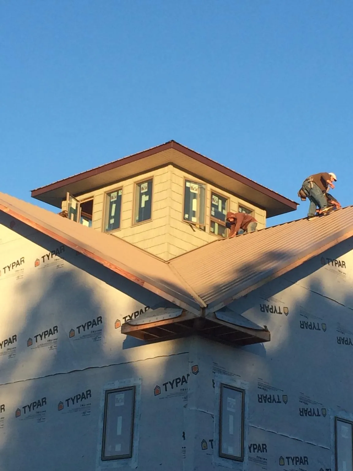 Roofers working around a rooftop cupola on a new metal roof at sunset — Roof Waterproofing in Muncie by Roofing Brothers